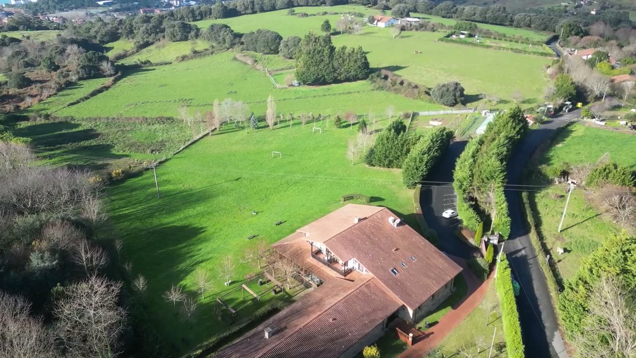 Finca Larrakoetxea entre prados en la costa de Bizkaia, con su camino de acceso y aparcamiento